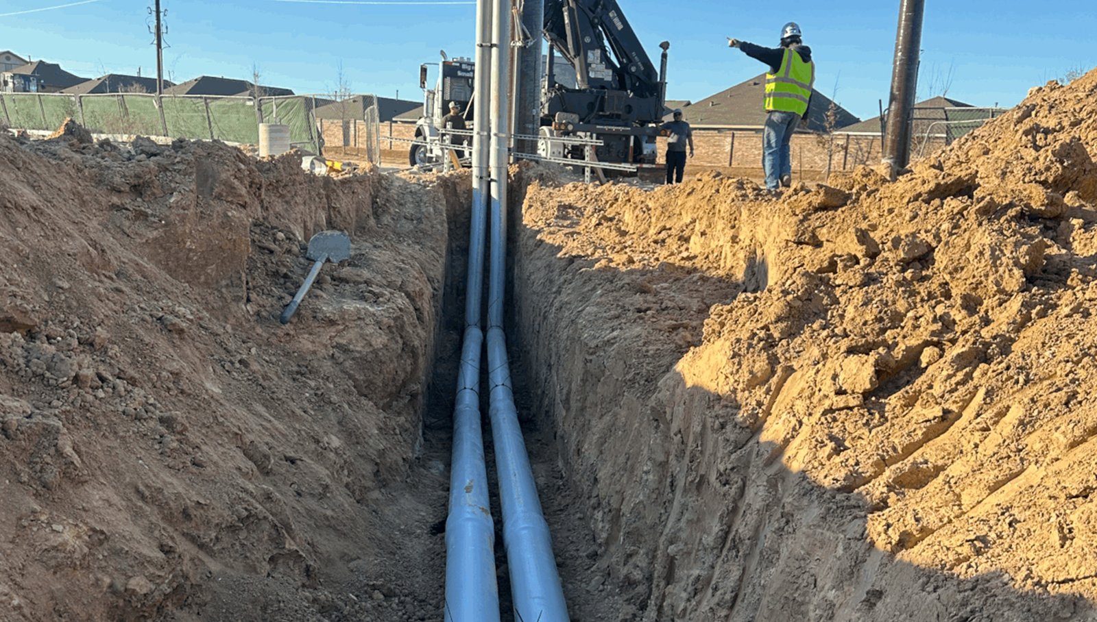 compact excavator installing conduit near foundation Houston